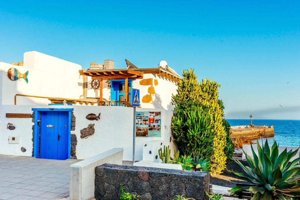 a white building with a blue door next to the ocean at Eco Fisherman's Seafront Cottage in Arrieta