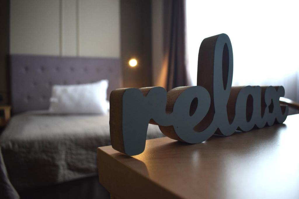 a wooden sign that says love sitting on a table next to a bed at Vila Camino in Satu Mare