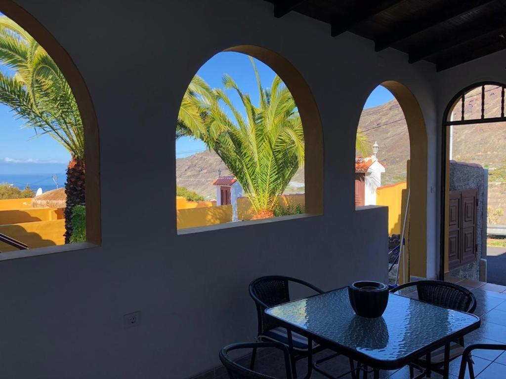 einen Tisch und Stühle in einem Zimmer mit 3 Fenstern in der Unterkunft Apartamentos Casa Rosán, junto a la Caldera de Taburiente in El Paso