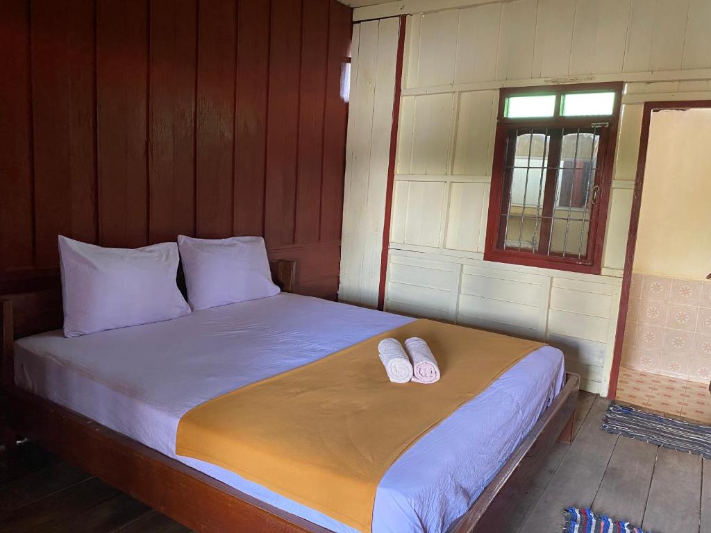 1 dormitorio con 1 cama con 2 zapatillas en Souksanh Guesthouse, en Ban Donsôm