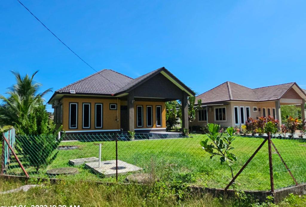 une maison avec une pelouse verte devant elle dans l'établissement Homestay Rumah Tengok Jelawat Bachok, à Bachok