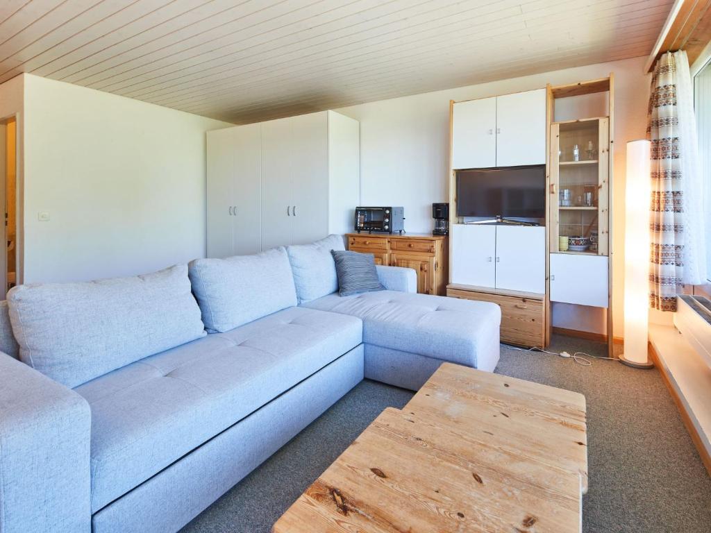 sala de estar con sofá azul y cocina en Studio Dixence 219 by Interhome, en Les Collons