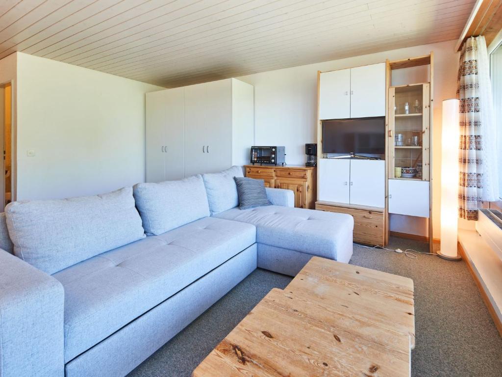a living room with a blue couch and a kitchen at Studio Dixence 219 by Interhome in Les Collons