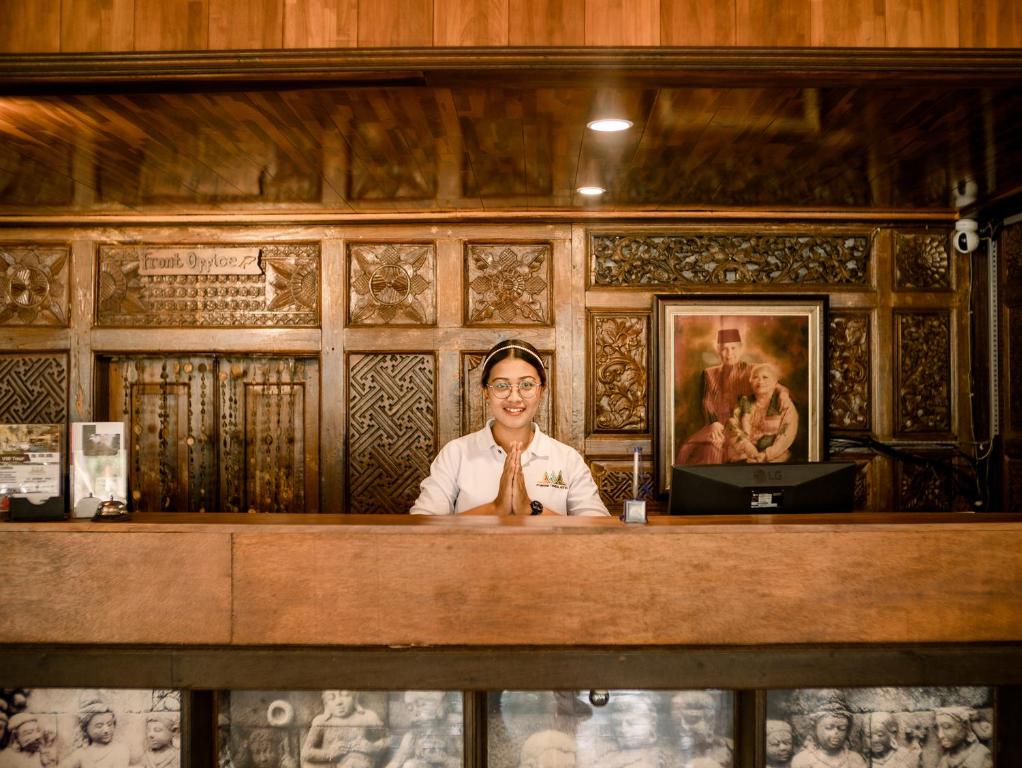 a woman sitting at a counter in a room at Pondok Tingal Borobudur in Magelang