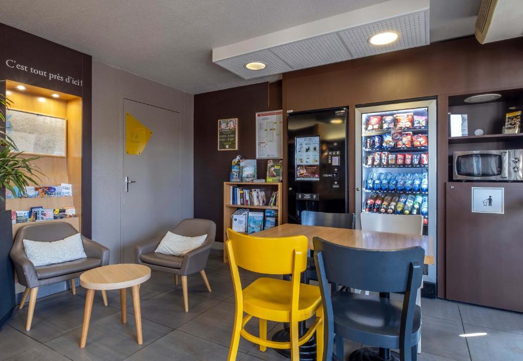 a restaurant with yellow chairs and a table at B&B HOTEL La Rochelle Angoulins in Angoulins-sur-Mer
