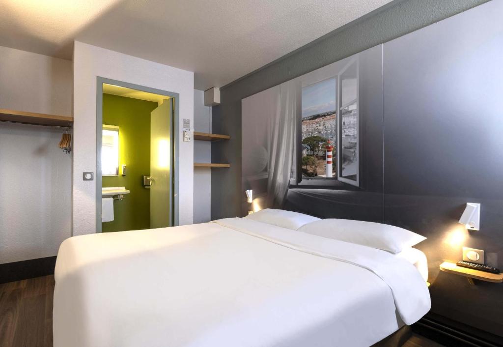 a bedroom with a large white bed and a window at B&B HOTEL La Rochelle Angoulins in Angoulins-sur-Mer