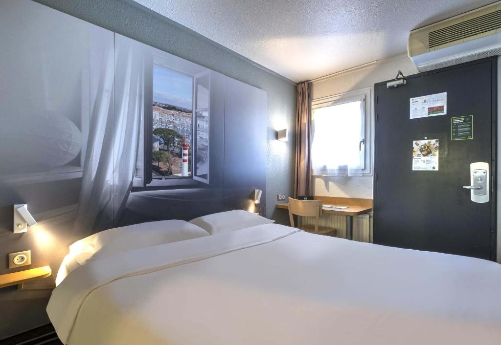 - une chambre avec un grand lit blanc et une fenêtre dans l'établissement B&B HOTEL La Rochelle Angoulins, à Angoulins-sur-Mer