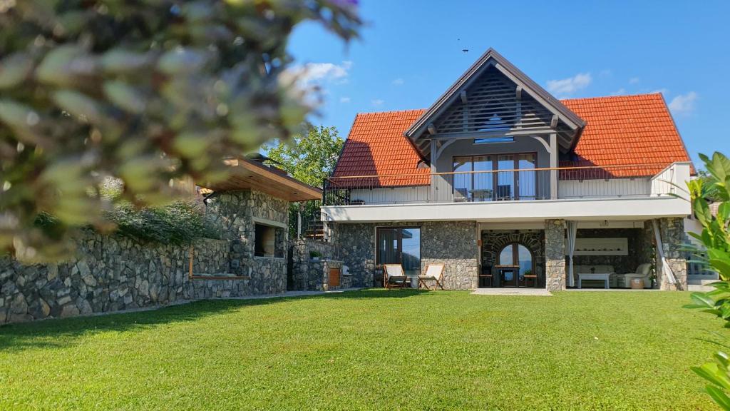 ein Steinhaus mit einem orangenen Dach und einem Hof in der Unterkunft Vineyard cottage Lan na Hribu in Semič