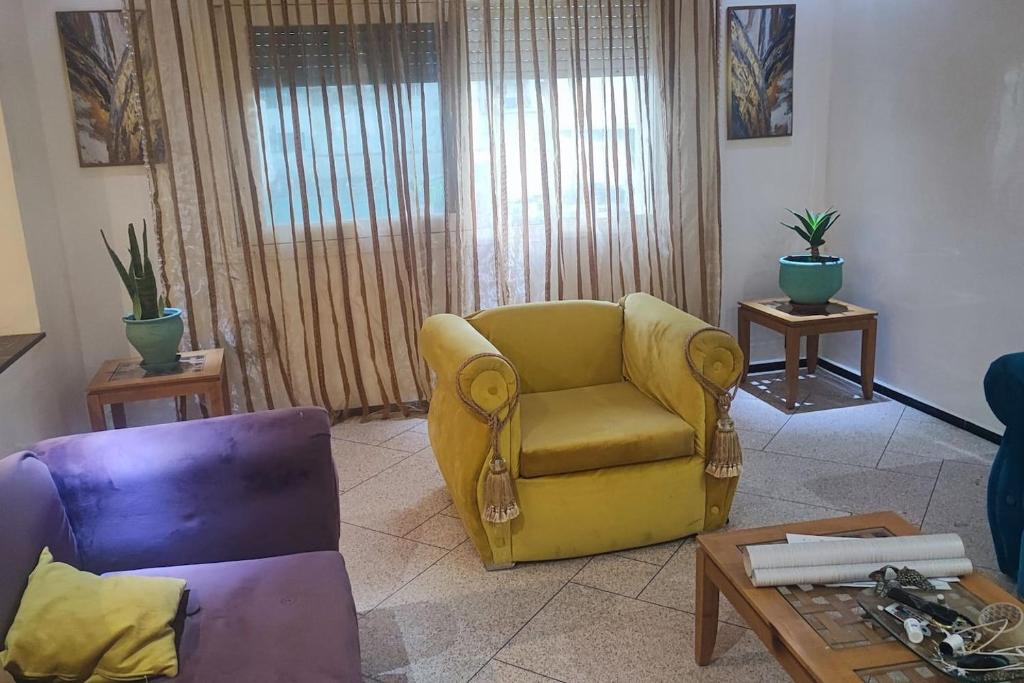 a living room with a yellow chair and a table at Ali's App Arts in Kenitra