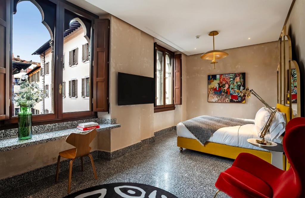 フィレンツェにあるHotel Calimala Florenceのベッドとテレビと窓のある寝室