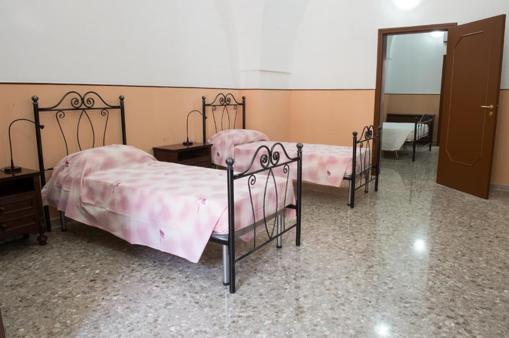 Habitación con 3 camas, sábanas rosas y espejo. en B&b Pozzi Dolci, en Aradeo