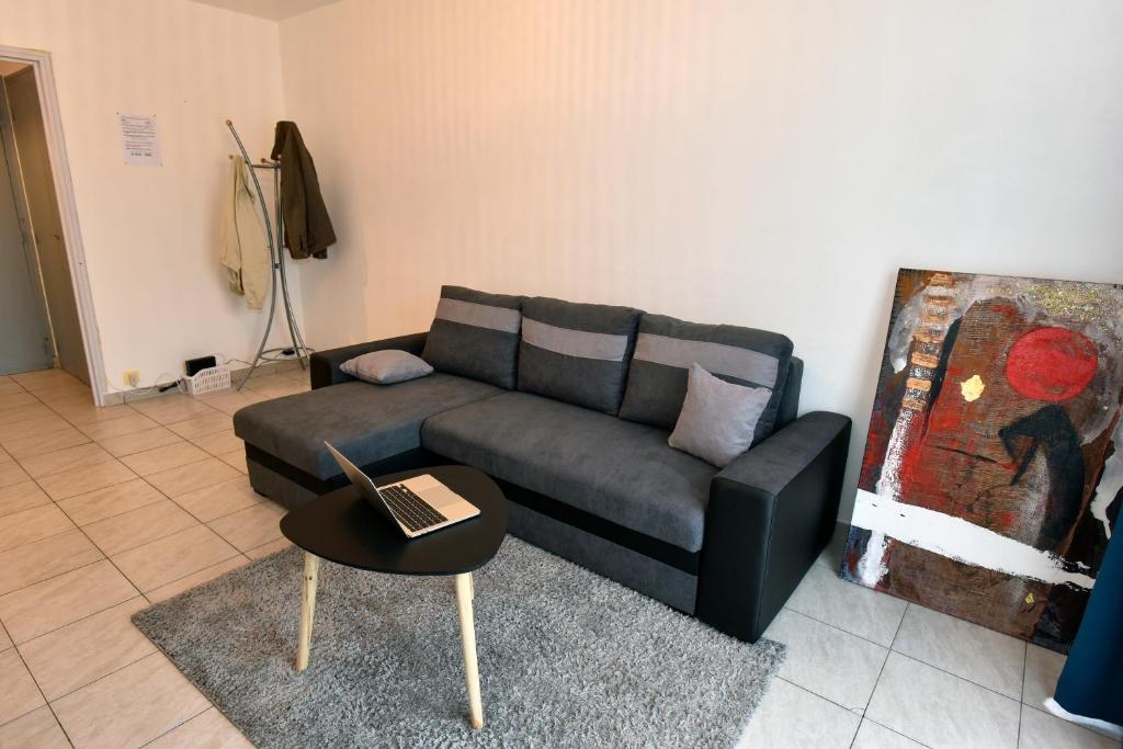 sala de estar con sofá y mesa con ordenador portátil en BEAU T3 SPACIEUX PROCHE CENTRE ViLLE, en Brive-la-Gaillarde
