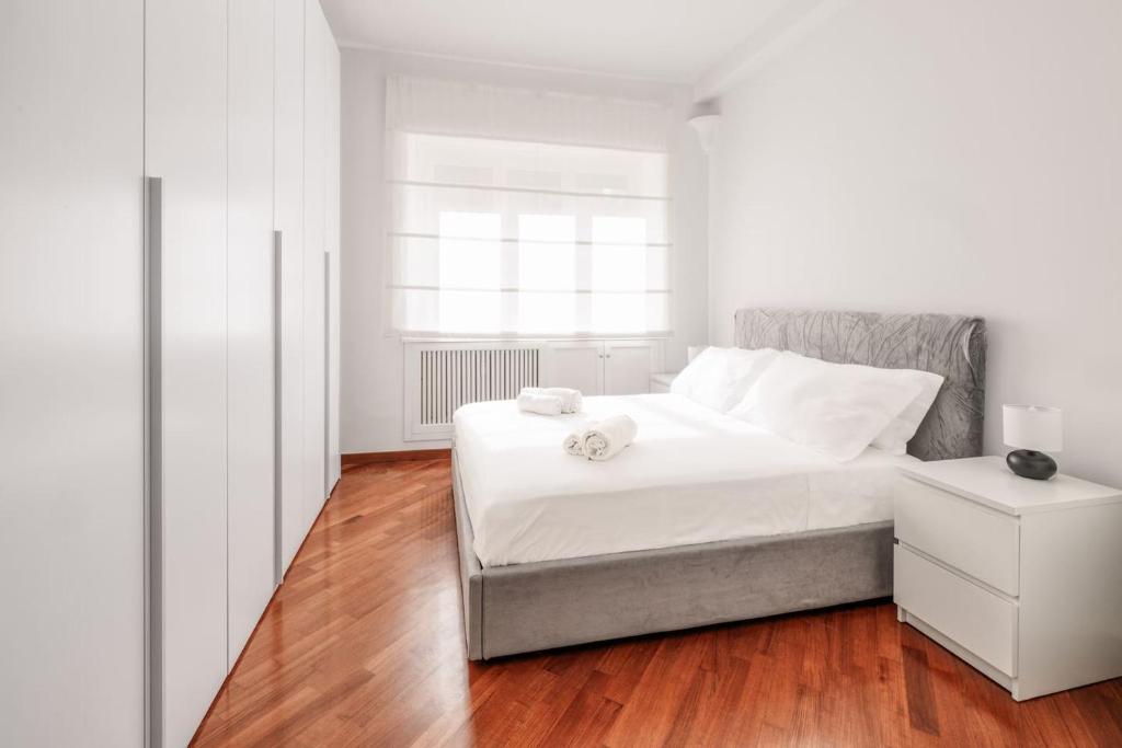 een witte slaapkamer met een bed en een houten vloer bij Vatican Museum Apartment - Zen Real Estate in Rome