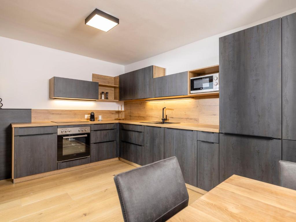 a kitchen with wooden cabinets and a table and chairs at Apartment Apartments Austria-2 by Interhome in Söll