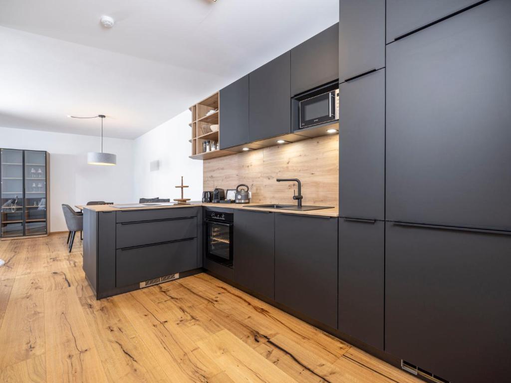 a kitchen with black cabinets and a wooden floor at Apartment Apartments Austria-5 by Interhome in Söll