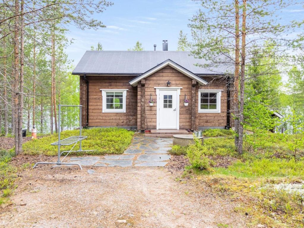 een blokhut met een witte deur in het bos bij Holiday Home Koppelomaa by Interhome in Puolanka