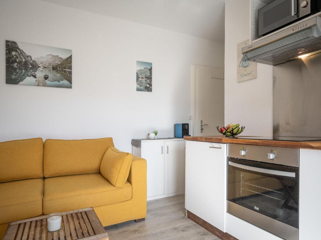 een woonkamer met een gele bank in een keuken bij Studio Beau séjour 15 by Interhome in Ovronnaz