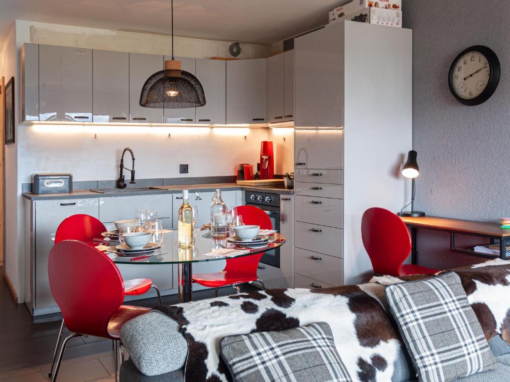 a kitchen with a table and red chairs in a room at Apartment Victoria 1 D2 by Interhome in Nendaz