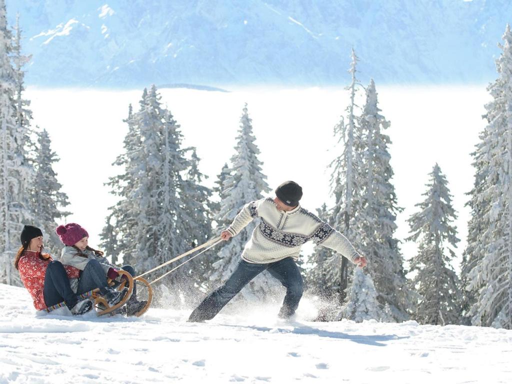 a man pulling a woman on a sled in the snow at Apartment Verditz alpe maritima Ski & See - Top 1 by Interhome in Annenheim