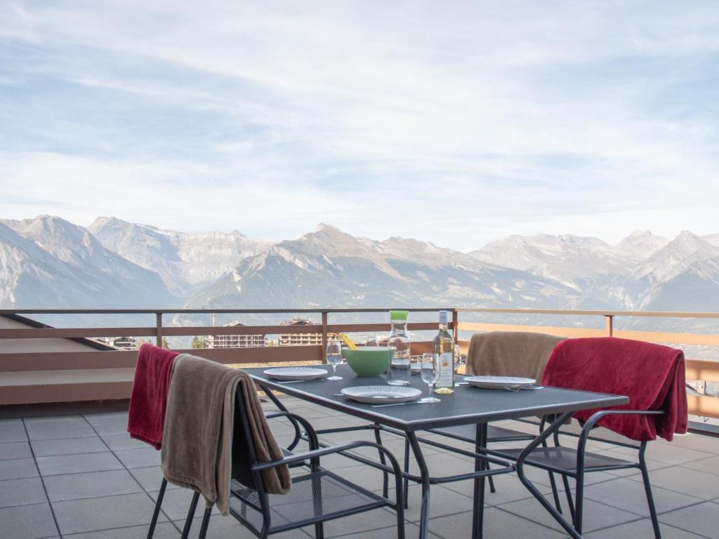 a table and chairs on a balcony with a view of mountains at Apartment Olympic C7 by Interhome in Nendaz
