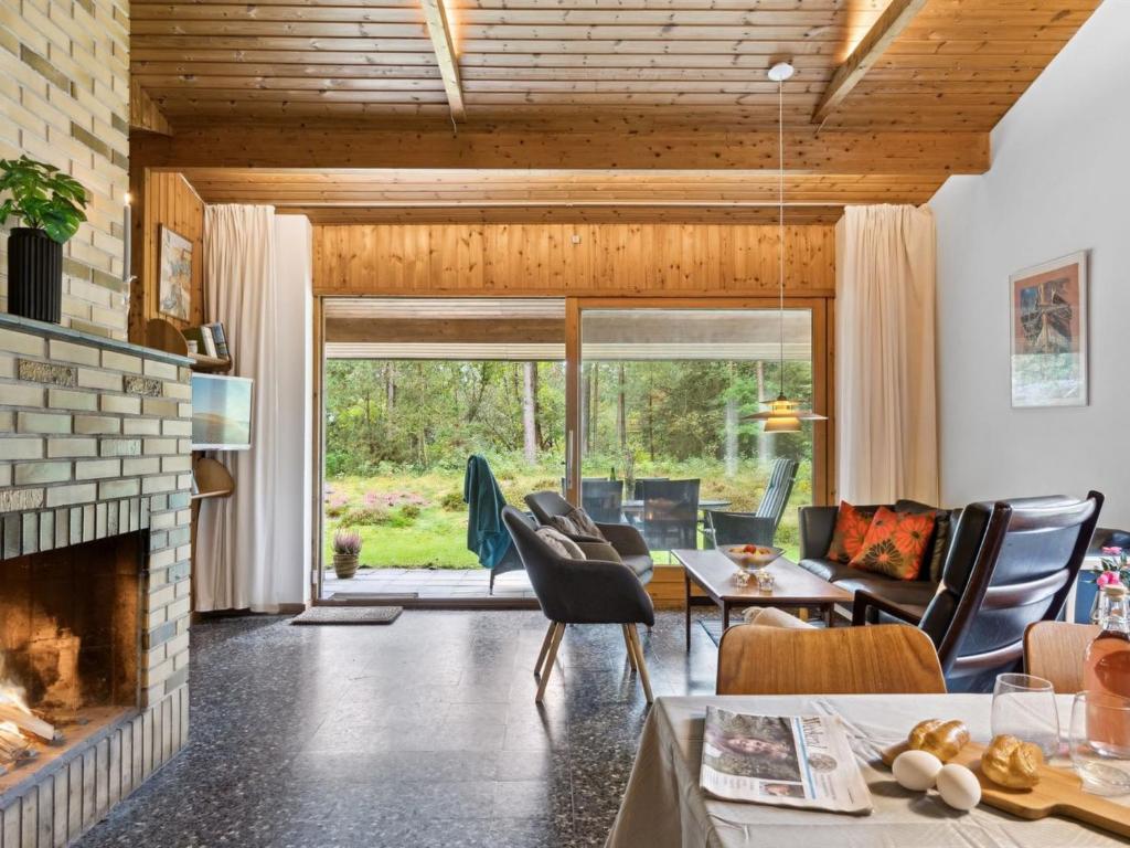 ein Wohnzimmer mit einem Kamin, einem Tisch und Stühlen in der Unterkunft Holiday Home Fulla - 650m from the sea in Sealand by Interhome in Højby