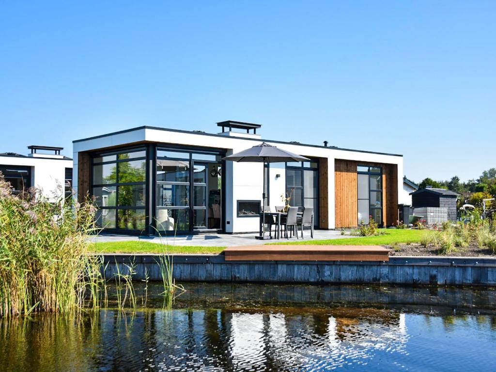 una casa moderna con un estanque frente a ella en Holiday Home Villa Nautica 6 persoons by Interhome, en Loosdrecht