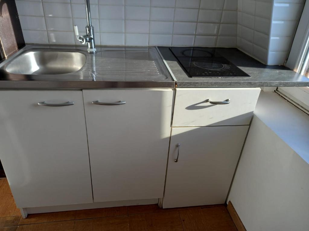uma pequena cozinha com armários brancos e um lavatório em Pavillon au pied du RER B à 5 minutes de Paris et 30 MN Stade de France em Cachan