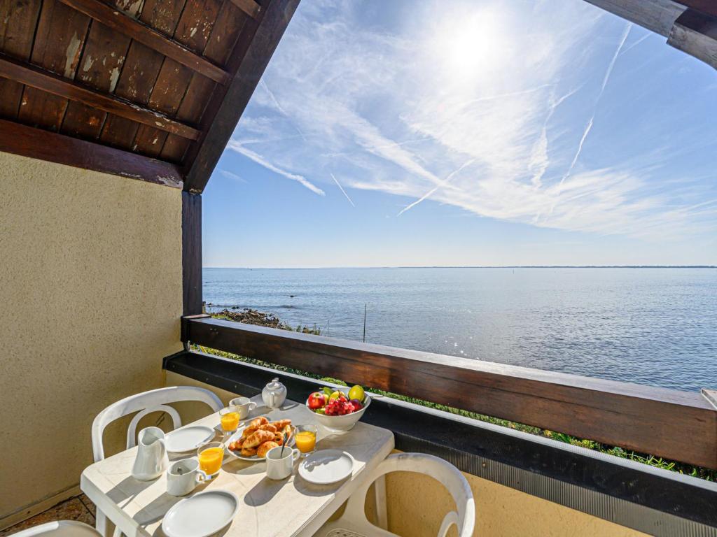a table with a bowl of fruit on a balcony with the ocean at Apartment Plein Océan-2 by Interhome in Carnac