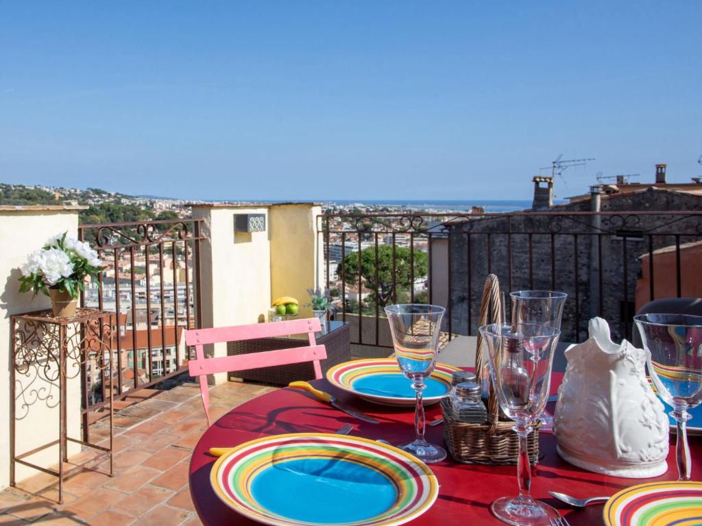 une table avec des assiettes et des verres à vin sur un balcon dans l'établissement Apartment Doux Bijou by Interhome, à Cagnes-sur-Mer