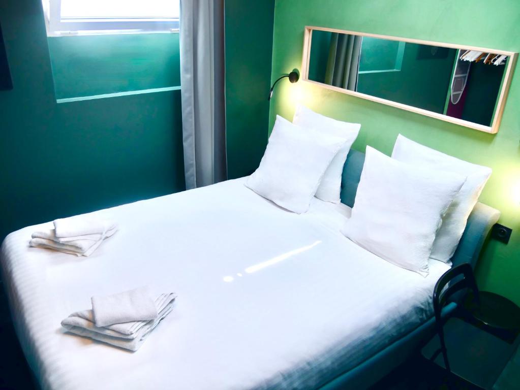 um quarto com uma cama branca e 2 chinelos em L'Emeraude - Paris 19ème Arrondissement em Paris