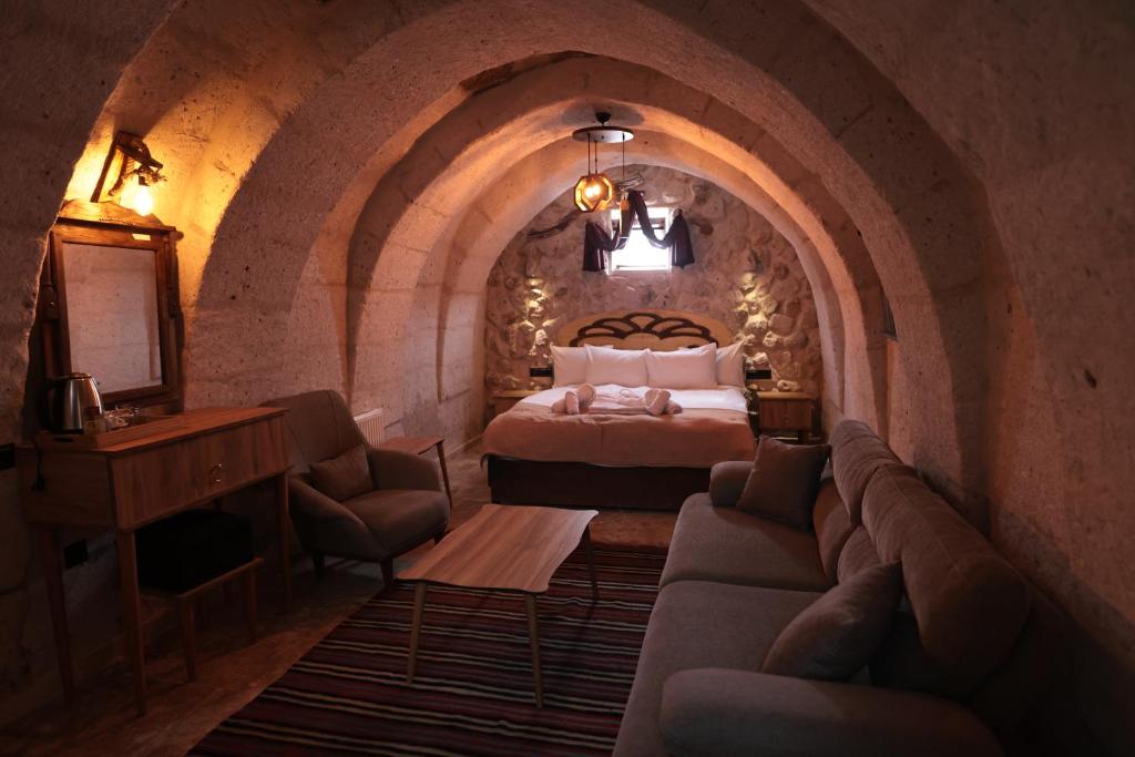 a bedroom with a bed and a couch in a room at Stone Owl Otel & Restaurant in Uçhisar