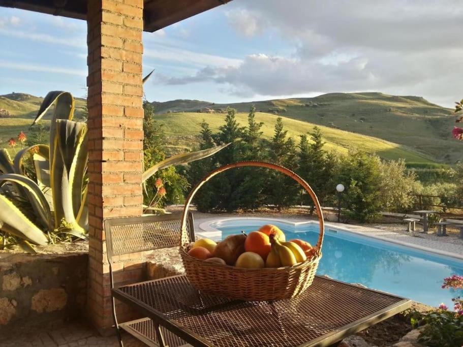 ein Obstkorb auf einem Tisch neben einem Pool in der Unterkunft San Todero Country House in Centuripe