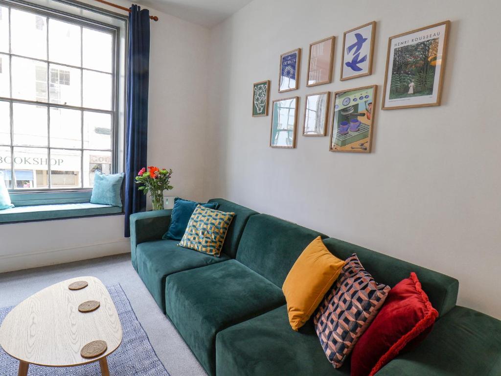 uma sala de estar com um sofá verde com almofadas coloridas em Book House em Whitby