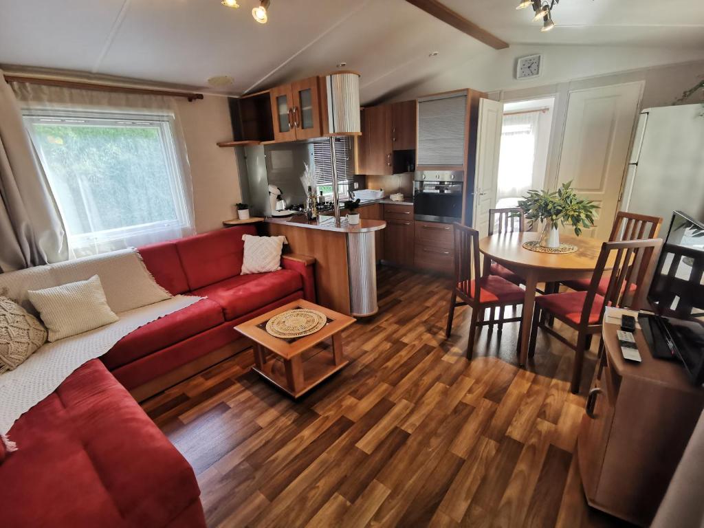 uma sala de estar com um sofá vermelho e uma cozinha em Mobil Home proche de la mer em Saint-Martin-Plage