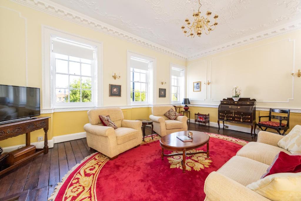a living room with chairs and a red rug at Stunning & spacious Georgian town house in St Neots town centre with parking in Saint Neots