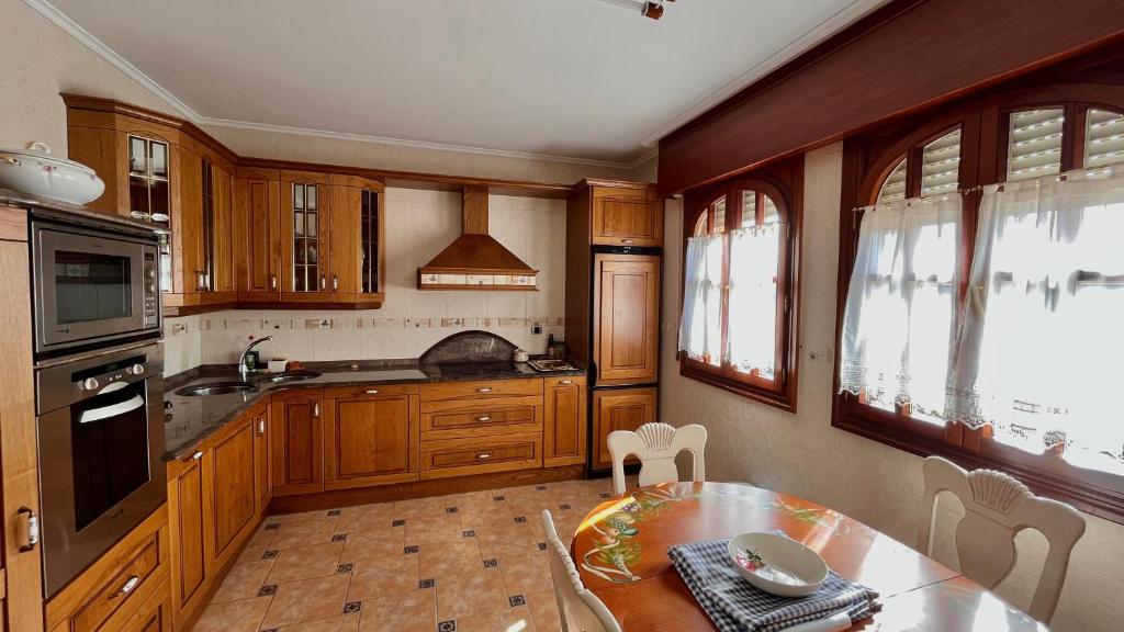 a kitchen with wooden cabinets and a table with a dining room at Villa Artegoikoa in Ibarrangelu