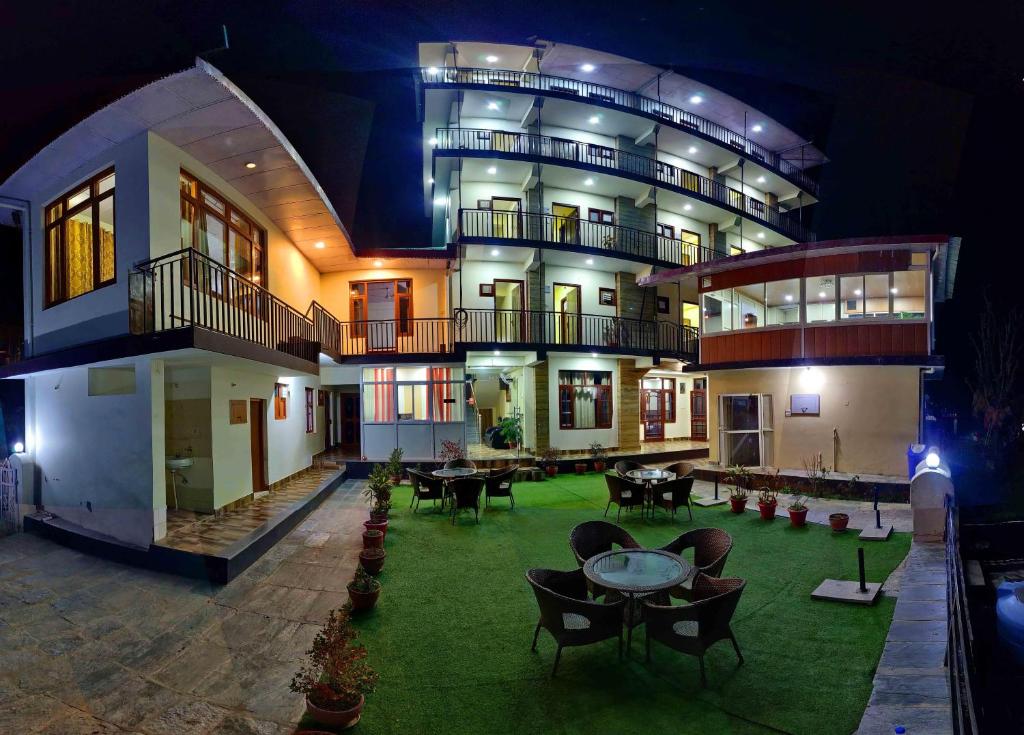a large building with tables and chairs in a yard at Hotel Harmony Blue Mcleodganj, Dharamshala in Dharamshala