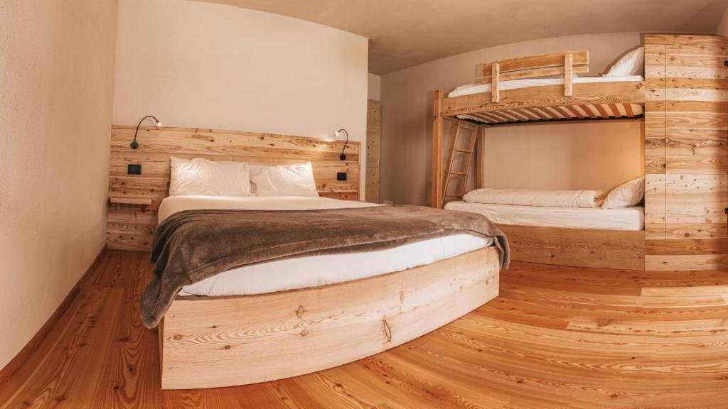 two bunk beds in a room with wooden floors at B&B Maso Ghirola in Pinzolo