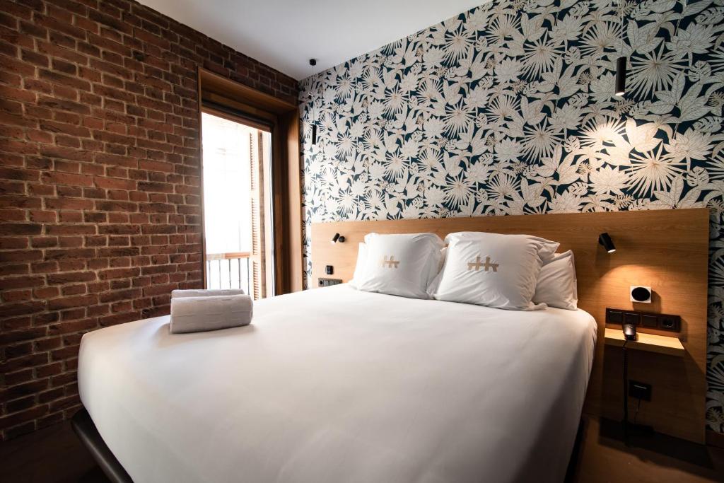 a bedroom with a white bed with a brick wall at Hotel Atari in Donostia-San Sebastián