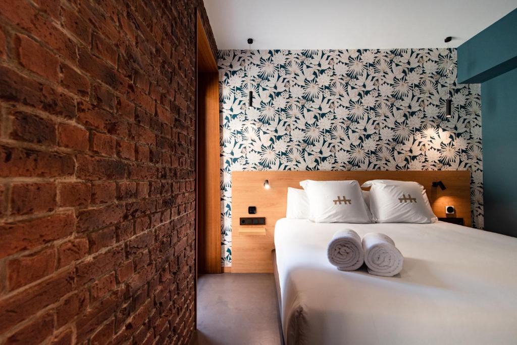 a bedroom with a white bed and a brick wall at Hotel Atari in Donostia-San Sebastián