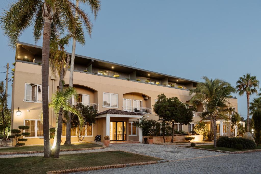 un grand bâtiment avec des palmiers devant lui dans l'établissement Quinta do Eden, à Vagos