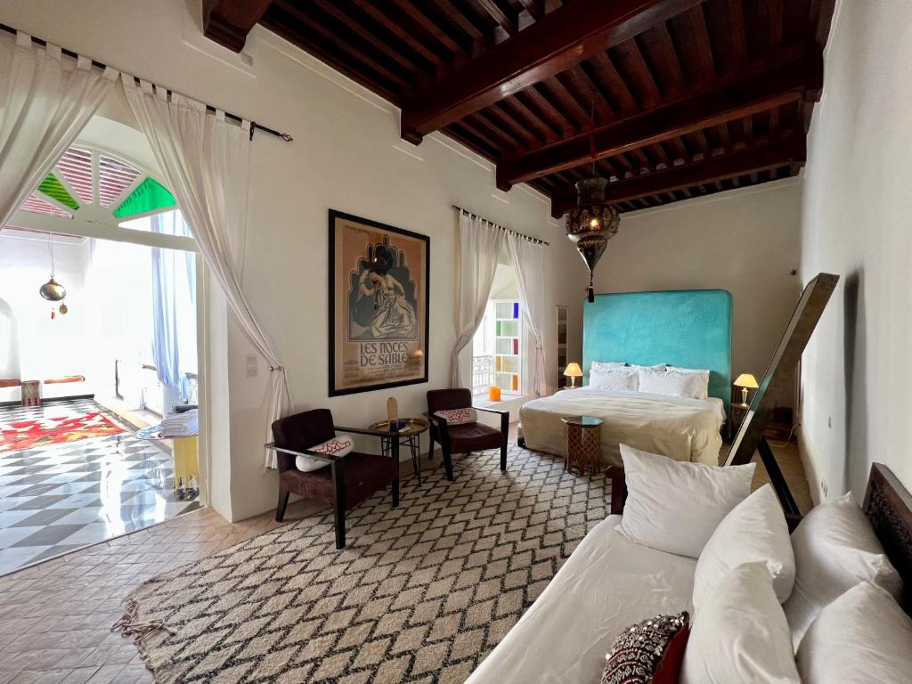 a bedroom with two beds and a table in a room at Riad Tizwa Marrakech in Marrakesh