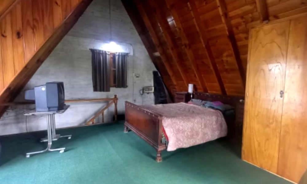 - une chambre mansardée avec un lit et une télévision dans l'établissement Cabaña frente al Río, à Necochea