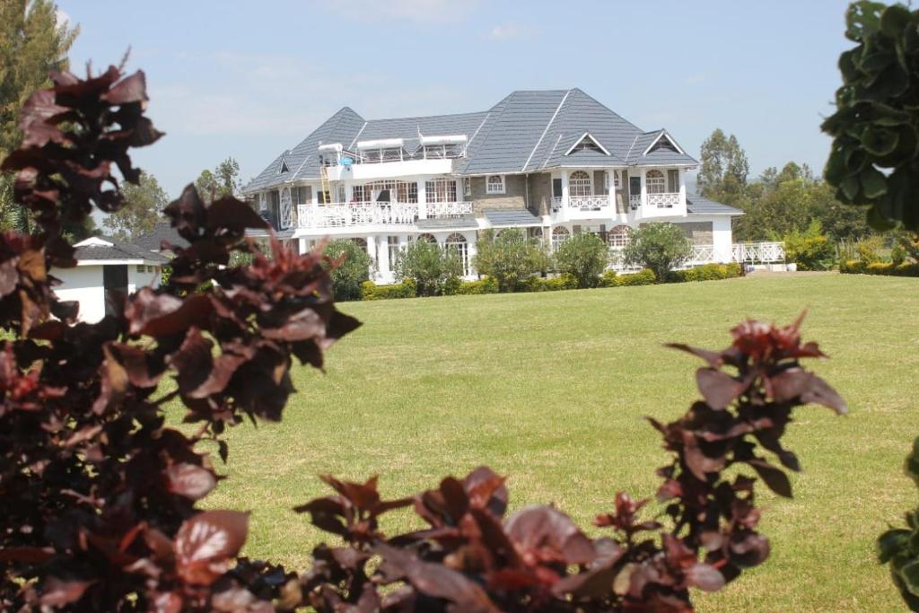 uma grande casa branca com um grande quintal em Balmoral Beach Hotel Kisumu em Kisumu