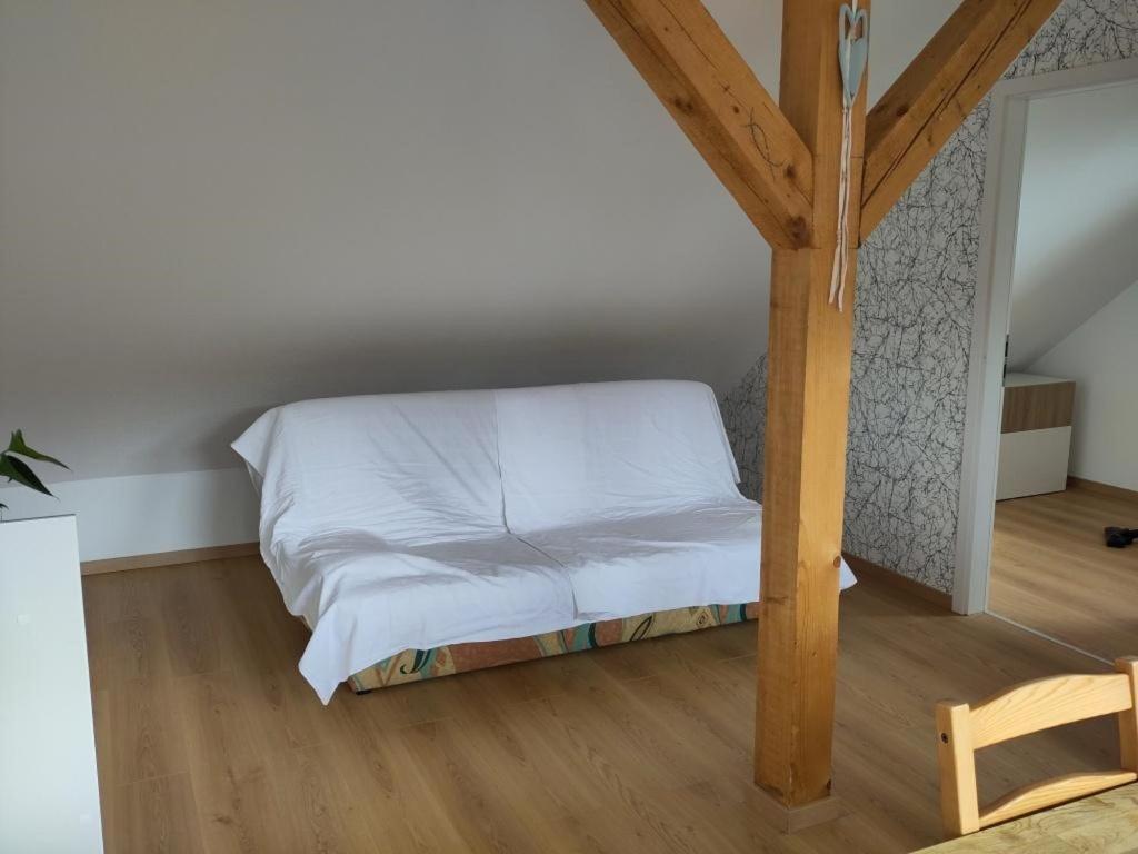 a bedroom with a bed with white sheets and a wooden floor at Ferienwohnung Lärchennest 