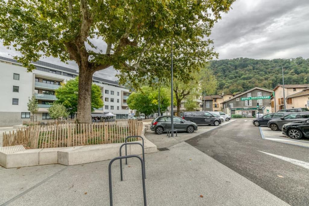 a parking lot with cars parked next to a tree at Le Charme Antique¶ Belle maison¶ Centre Gières in Gières