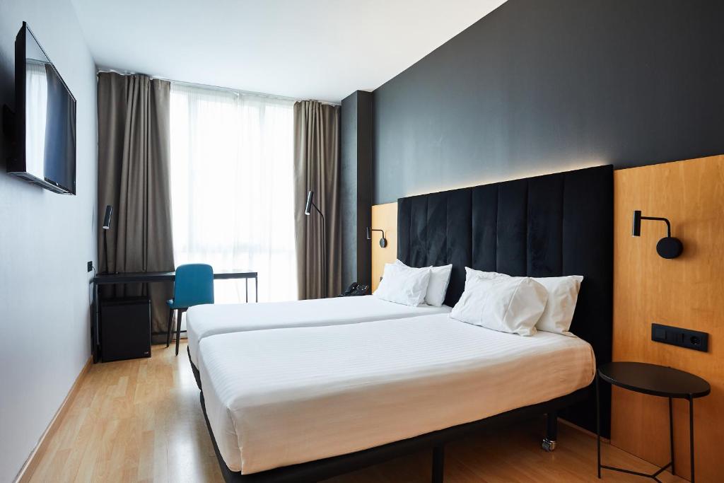 una habitación de hotel con una cama grande con sábanas blancas en Silken Sant Gervasi en Barcelona