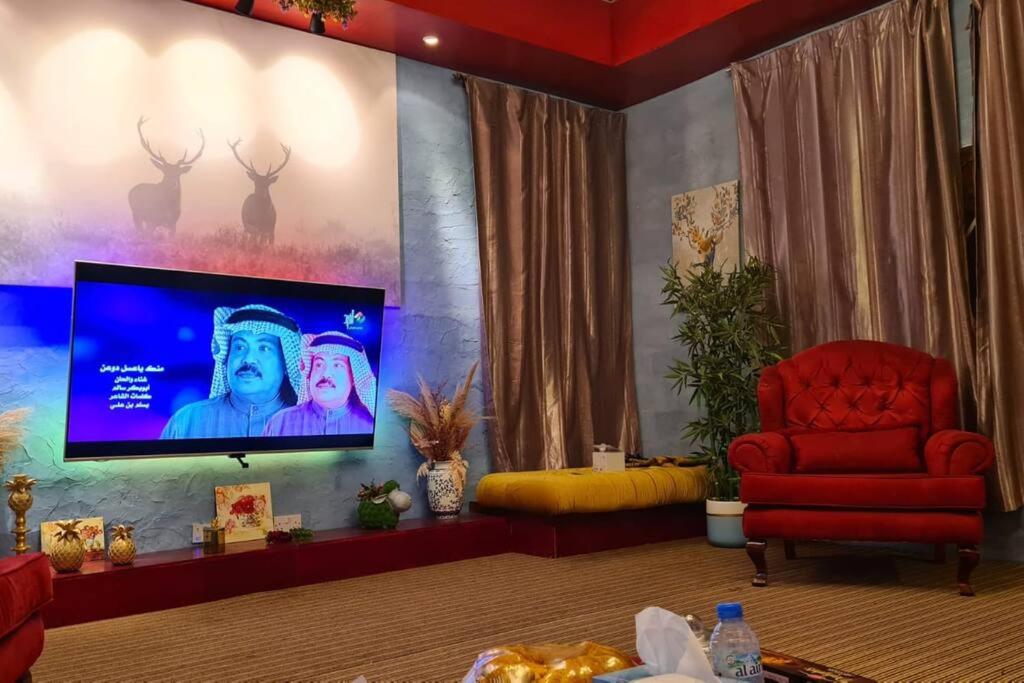 a living room with a red chair and a flat screen tv at amazing view large dunes nearby in Liwa