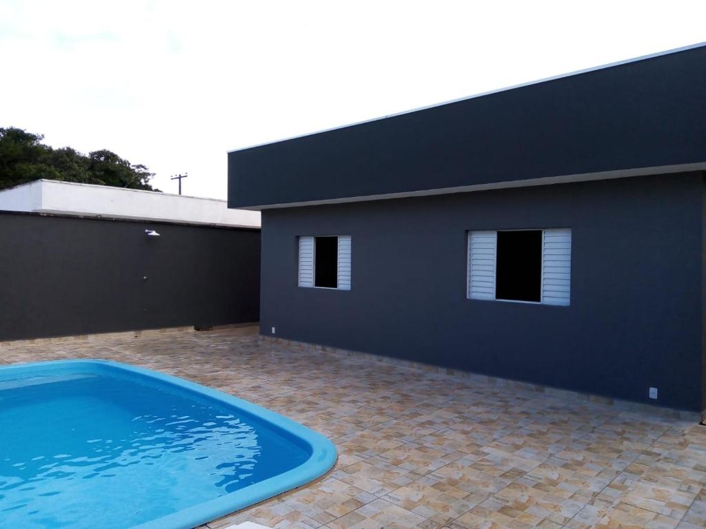 Casa com piscina em condomínio fechado في بيرويبي: منزل به مسبح امام مبنى