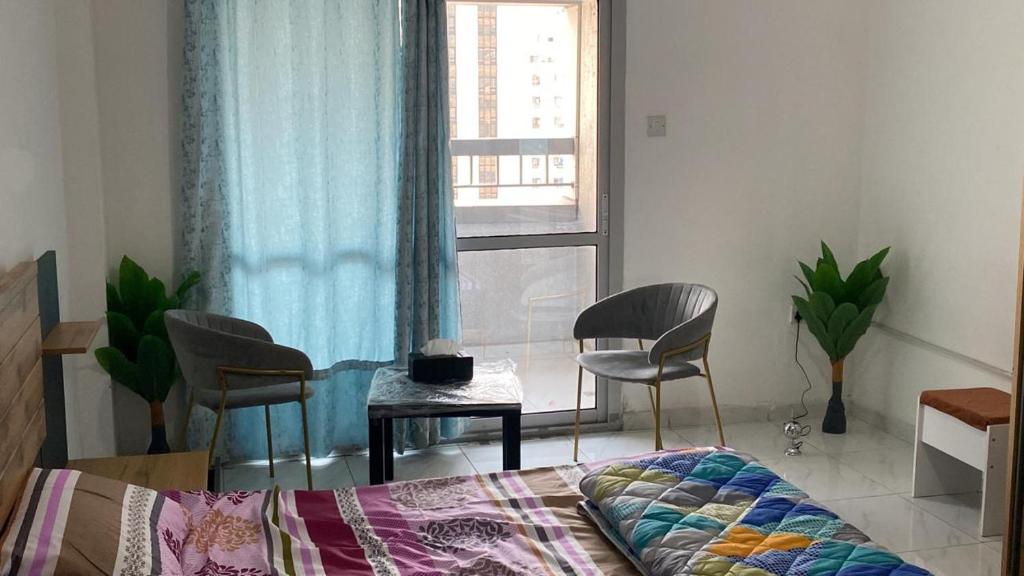 a bedroom with a bed and chairs and a window at Sharing motel rooms in Abu Dhabi